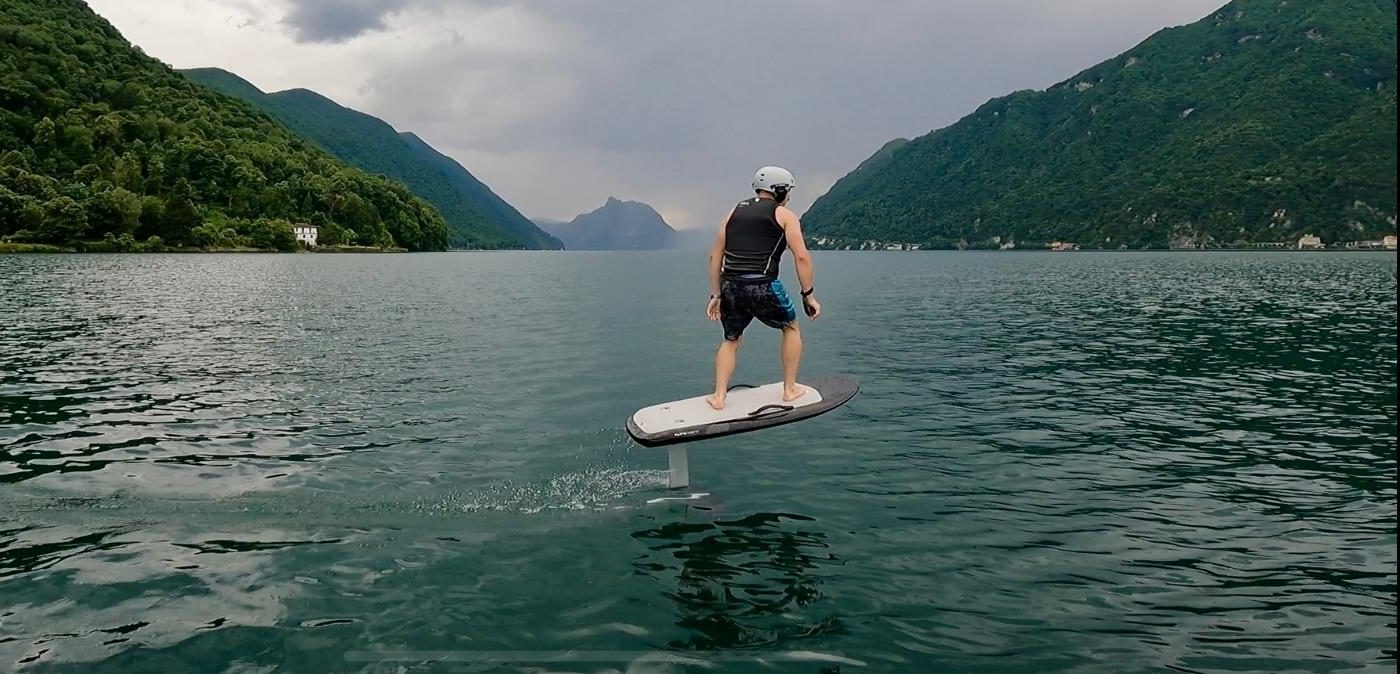 Rider in e-foil sul lago tra le montagne